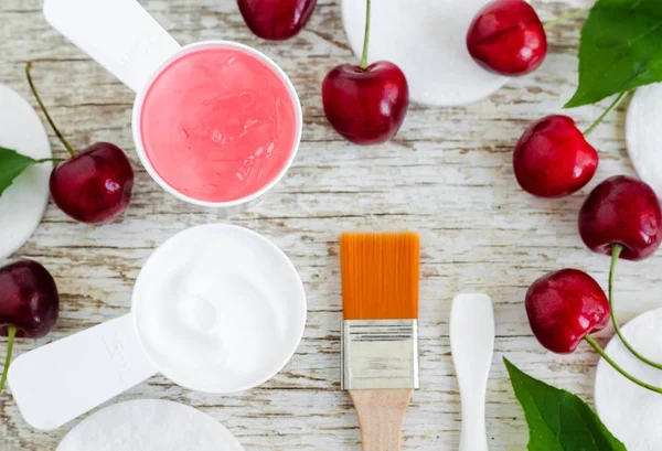 Yüz kremi (maske) ile iki küçük top ve tatlı kiraz ile pembe jel ayıklayın. Spa ve doğal cilt bakım kavramı. Üstten görünüm, kopya alanı.