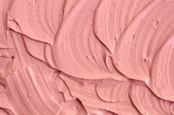 Soft pink cosmetic clay (facial mask, cream) texture close up, selective focus. Abstract background with brush strokes.