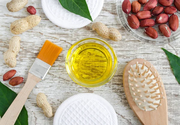 Small glass bowl with peanut (groundnut) oil for preparing face and hair mask. Natural skin and hair mask recipe. Ingredients of homemade cosmetics. Top view, copy space. — Stock Photo, Image