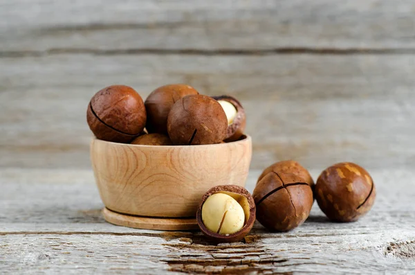 Small wooden bowl with macadamia nuts on the old wooden background. Copy space. — Stock Photo, Image