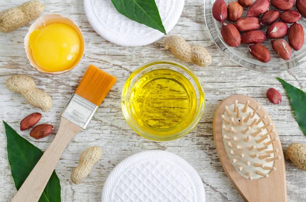 Tigela de vidro pequeno com óleo de amendoim (amendoim) e gema de ovo cru. Rosto natural e receita máscara de cabelo. Ingredientes de cosméticos caseiros. Vista superior, espaço de cópia . — Fotografia de Stock