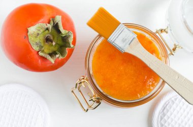 Ev yapımı Trabzon hurması (kaki) yüz maskesi bir cam kavanoz ve kozmetik fırça. DIY Güzellik Bakımı ve spa. Üstten görünüm, kopya alanı. 