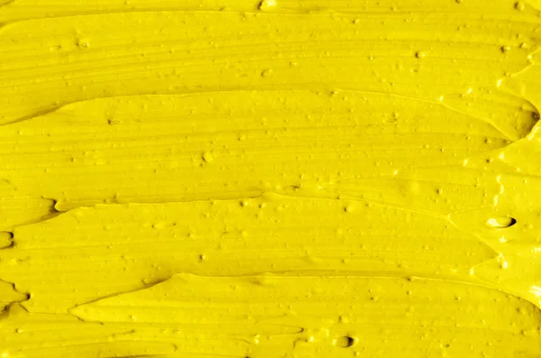 Yellow cosmetic facial mask (cream, body scrub) texture close up, selective focus. Abstract background with brush strokes