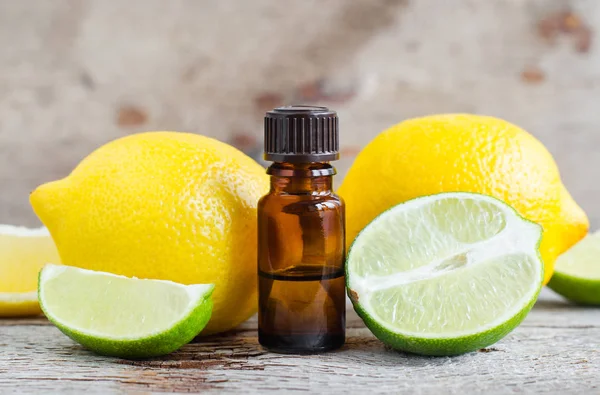 Small bottle of essential citrus (lemon and lime) oil on the old wooden background. Aromatherapy, spa and herbal medicine ingredients. Copy space. — Stock Photo, Image
