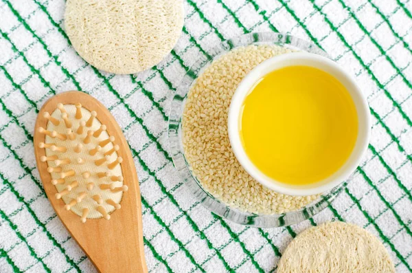 Sesame oil and seeds in the small bowl. Wooden hairbrush. Ingredients of diy face and hair masks and moisturizers. Homemade beauty treatments recipe. Top view, copy space. — Stock Photo, Image