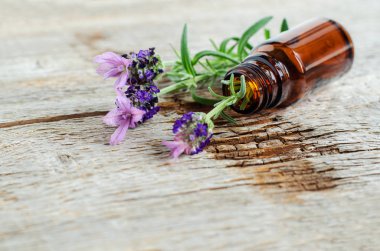 Uçucu lavanta yağı ile küçük bir şişe. Lavandula çiçekleri yakın. Aromaterapi, spa ve bitkisel ilaç maddeleri. Eski ahşap arka plan. Kopyalama alanı. 