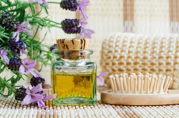 Vintage glass bottle with aroma lavender oil and wooden hair brush. Topped lavender flowers close up. Natural skin and hair care. DIY beauty treatments and spa concept. Copy space.