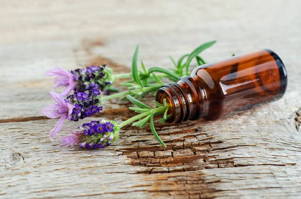 Uçucu lavanta yağı ile küçük bir şişe. Lavandula çiçekleri yakın. Aromaterapi, spa ve bitkisel ilaç maddeleri. Eski ahşap arka plan. Kopyalama alanı.  