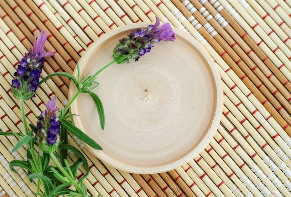 Piring kayu kecil sebagai tempat untuk teks dan dihiasi bunga lavender di latar belakang bamgoo mat. Herbarium, obat herbal dan konsep botani. Tampilan atas, ruang penyalinan . — Stok Foto