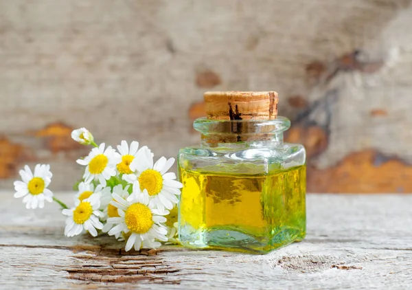 Roma papatya uçucu yağ (özü, tentür, infüzyon) ile Vintage şişe. Eski ahşap arka plan. Aromaterapi, spa ve bitkisel ilaç kavramı. Kopyalama alanı. 