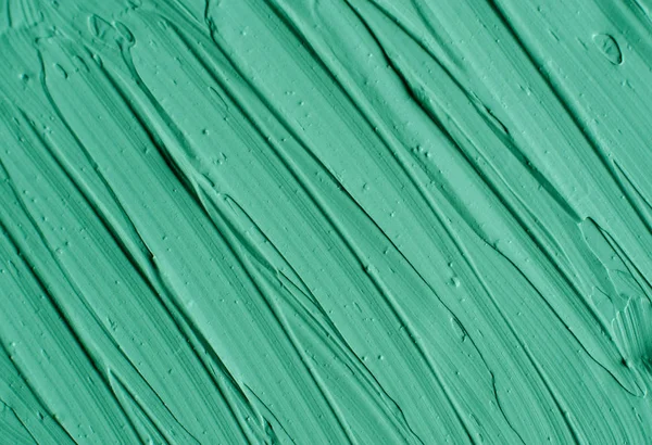 Green cosmetic clay (facial mask, cream, body wrap) texture close up, selective focus. Abstract background with brush strokes.