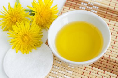 Kozmetik yağlı, karahindiba çiçekli ve pamuklu küçük bir kase. Doğal spa ve güzellik tedavi tarifi. Üst görünüm, alanı kopyala.