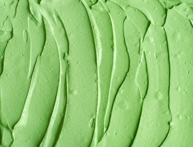 Yeşil kozmetik kil (salatalık yüz maskesi, avokado yüz kremi, yeşil çay eşleşmesi vücut ambalajı) yakından seçici odaklanma. Fırça darbeleriyle soyut arkaplan.   