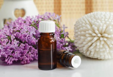 İki küçük şişe yağ (tentür, infüzyon, parfüm) ve leylak çiçekleri. Aromaterapi, spa ve bitkisel ilaçlar.. 