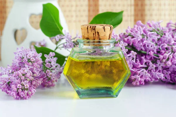 Vintage bottle with cork with essential oil (tincture, infusion, perfume) and lilac flowers. Aromatherapy, natural skin care, homemade spa and herbal medicine ingredients.