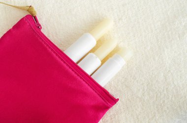 Küçük makyaj çantasında üç ruj izi var. Doğal dudak bakım konsepti. Üst görünüm, düz görünüm, kopyalama alanı.