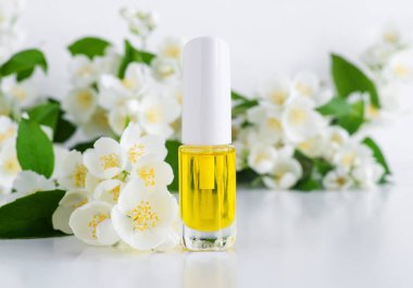 Kozmetik yağlı küçük şişe (masaj tırnağı yağı, tentür, infüzyon, özü) ve yasemin çiçekleri kapanıyor. Aromaterapi, doğal manikür, ev yapımı spa ve bitkisel tıp konsepti. Boşluğu kopyala.