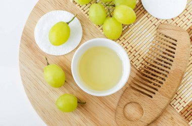 Üzüm tohumu yağı (üzüm sirkesi), pamuk pedleri ve ev yapımı saç maskesi hazırlamak için kullanılan ahşap saç fırçası malzemeleri, yüz toneri. Doğal güzellik tedavi tarifi, sıfır atık konsepti. Üst görünüm, alanı kopyala 