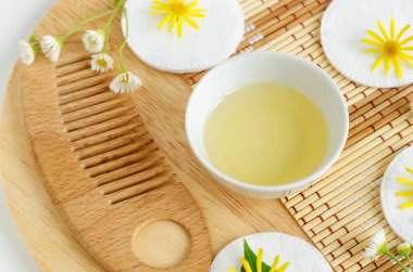 Kozmetik kaplı küçük beyaz kase (masaj, temizlik) aroma yağı, pamuk pedler, ahşap saç fırçası ve yabani çiçekler. Doğal cilt bakımı, ev yapımı spa ve güzellik tedavi tarifi. Üst görünüm, alanı kopyala. 