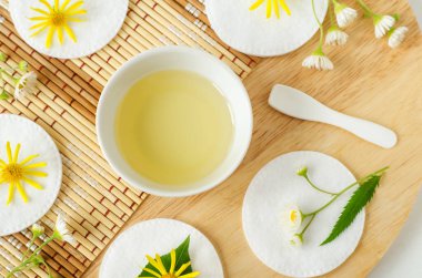 Kozmetik kaplı küçük beyaz kase (masaj, temizlik) aroma yağı, pamuk pedler ve yabani çiçekler. Doğal cilt bakımı, ev yapımı spa ve güzellik tedavi tarifi. Üst görünüm, alanı kopyala. 