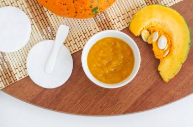 Küçük beyaz kâse ve pamuklu pedlerde taze kabak püresi. Ev yapımı yüz maskesi, doğal güzellik tedavisi ve spa tarifi. Üst Görünüm, Boşluğu Kopyala.  