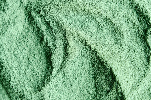 Green cosmetic clay powder (kelp facial mask, spirulina body wrap) texture close up, selective focus. Abstract background with brush strokes.