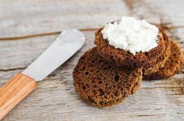 Krem peynirli küçük yuvarlak çavdar tostları. Eski ahşap arka plan, seçici odak, yakın plan.