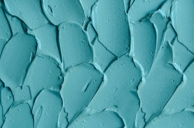 Açık mavi bentonit yüz kilini (aljinat maskesi, yüz kremi, vücut sargısı) kapat, seçici odaklanma. Fırça darbeleriyle soyut arkaplan. 