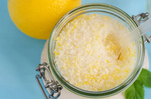 Homemade exfoliating scrub (foot soak) with sea salt, lemon juice and zest in the glass jar. DIY citrus beauty treatment and spa recipe. Top view, copy space.