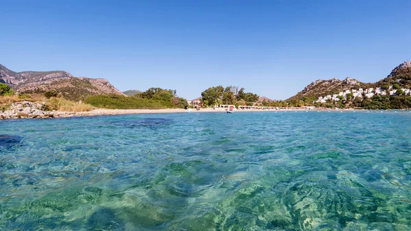 Clear turquoise water of Aegean sea and Caraincir beach. Beautiful Mediterranean seascape of ripple water with sunbeams reflections. Province of Mugla, Datca peninsula, Turkey