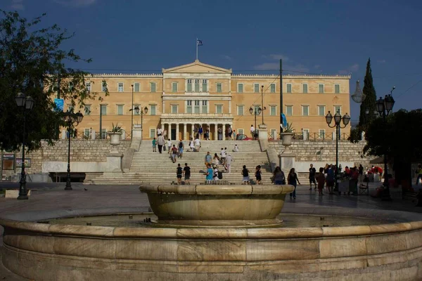 ATİNA, GREECE - 12 AĞUSTOS 2016: Atina 'daki Sintagma Meydanı' nda mermer çeşme, arkasında parlamento evi