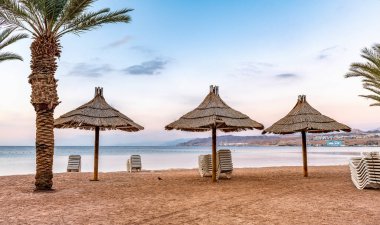 Deniz, kumlu sahil ve şemsiyeli yaz tatili 