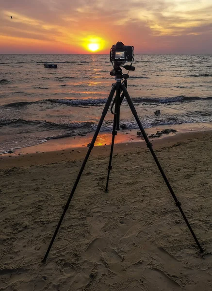 Baltık Denizi 'nin kumlu sahilinde gün doğumunda ön planda tripod ve fotoğraf makinesi olacak.