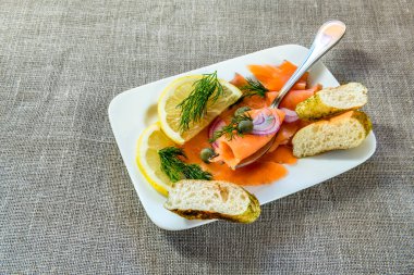 Aperatif kırmızı somon balığı dilimleri, limon ve soğan tabakta. 