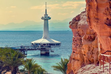 Coastal landscape with red rocks and building of underwater observatory, Red Sea, Middle East clipart