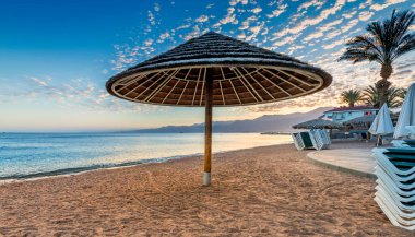 Kızıl Deniz 'in kumlu sahilinde sabah ön planda güneşlik, Orta Doğu