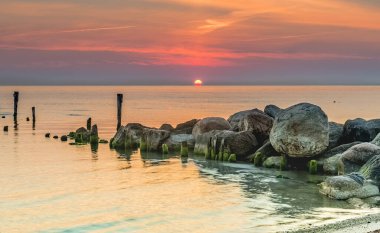 Kırık iskelesi olan kıyı manzarası, şafak vakti Baltık Denizi
