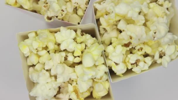 Palomitas de maíz en bolsas de papel gira sobre un fondo blanco — Vídeos de Stock