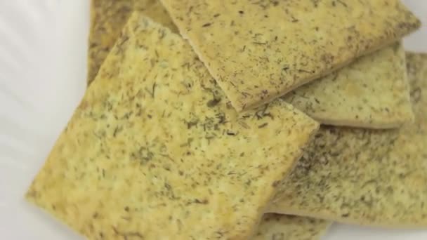 Pile of crackers sprinkled with herbs rotates on a white background. Top view — Stock Video