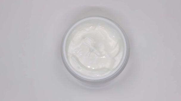 Weiße Kosmetikcreme im Glas rotiert auf weißem Hintergrund — Stockvideo