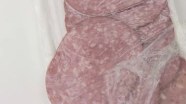 Dilimlenmiş salam beyaz bir porselen tabakta döner..