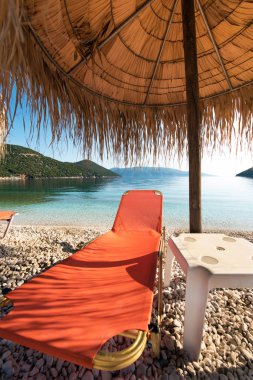 Antisamos Sahili'nden Kefalonia, Yunanistan Ionian Denizi'nin kıyısında şemsiyesi altında turuncu bir tembel soyut resimle. İnanılmaz yerler. Turistik Yerler.