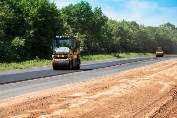 industrial landscape with rollers that rolls a new asphalt on the road. Repair work, complicated transport movement.