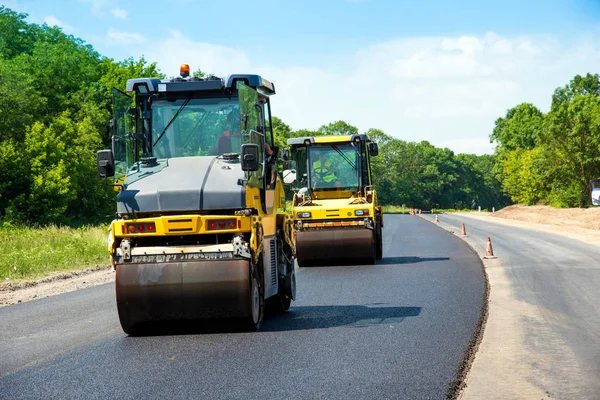 industrial landscape with rollers that rolls a new asphalt on the road. Repair work, complicated transport movement.