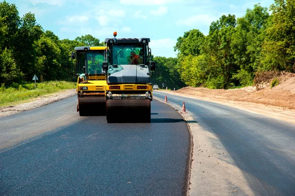 Yolda yeni bir asfalt yuvarlayan tekerlekli sanayi manzarası. Onarım, karmaşık ulaşım hareketi.