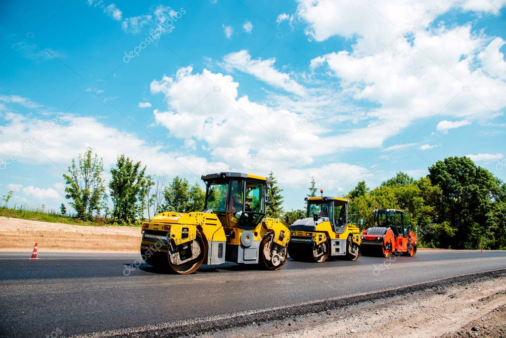 industrial landscape with rollers that rolls a new asphalt in the roadway. Repair, complicated transport movement.