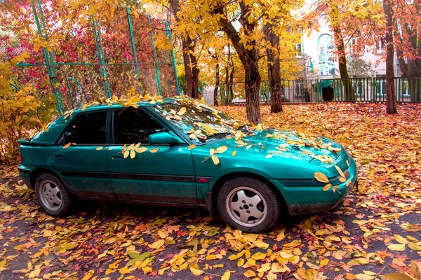 stock image abstract mystical image of an emerald car with a yellow autumn leaves the leaves on glass and hood