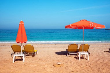 Şezlonglar ve Güneş deniz dalgaları ile sahilde üzerinde turuncu şemsiye ile soyut resim (gevşeme, uyum, tatil - kavram)