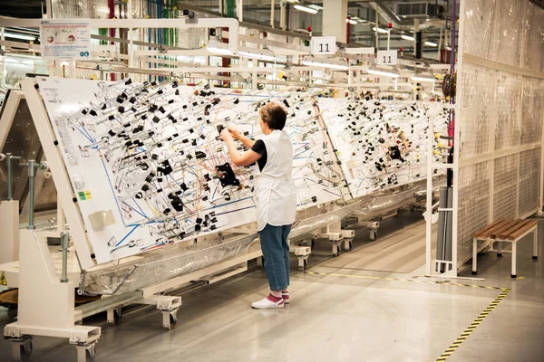 Bir işçi bir üretim odada elektrik kablolama araçlık bir modern fabrikasında üretim için standları