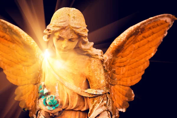 A fragment of ancient sculpture angel in a golden glow in the ol — Stock Photo, Image
